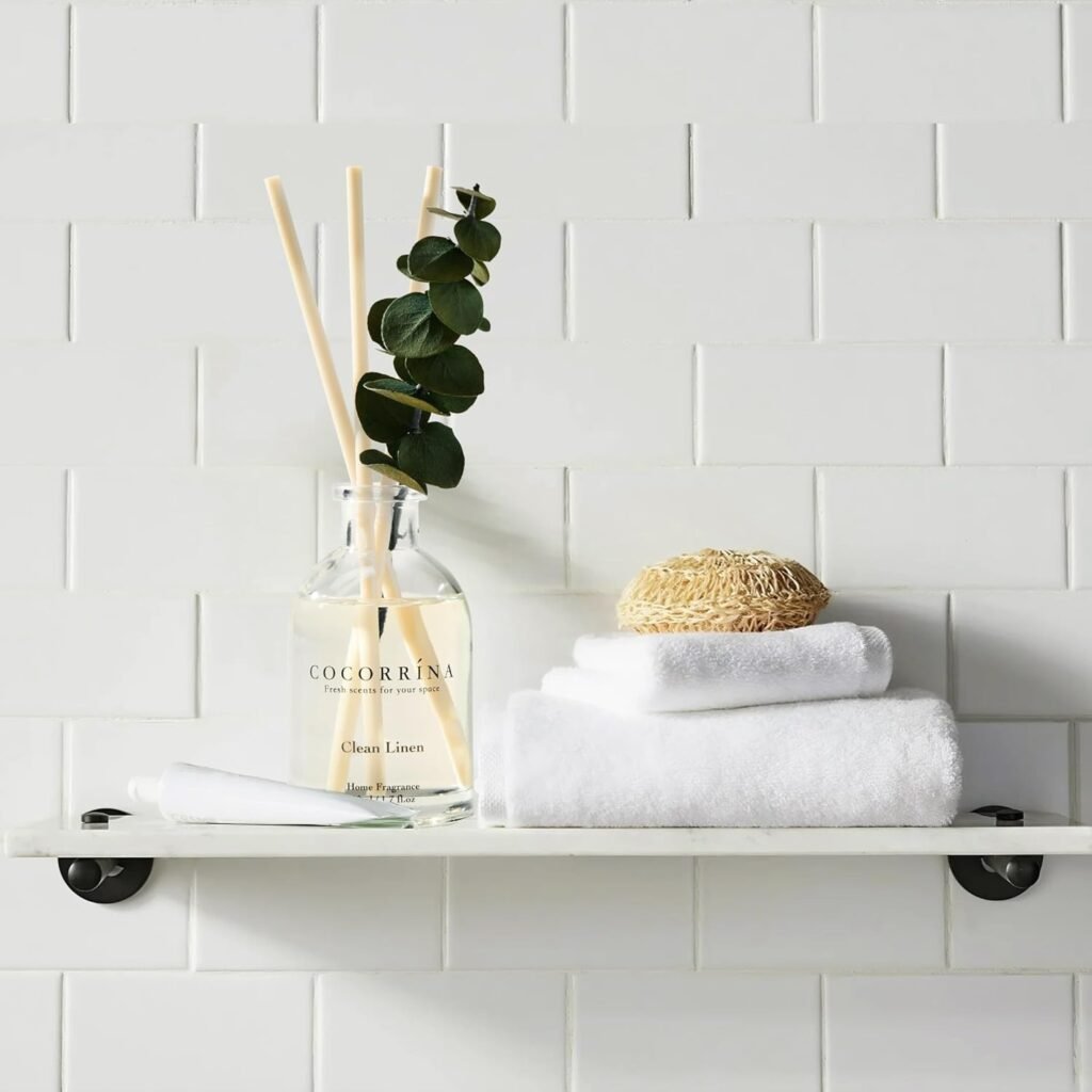 COCORRÍNA Clean Linen reed diffuser on bathroom shelf with white towels for a calm spa-inspired home atmosphere