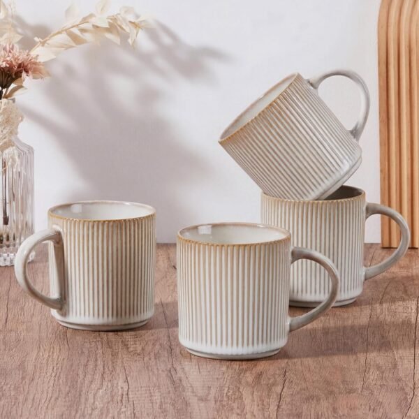 Creamy beige ribbed stoneware coffee mug set of four on a wooden table with soft neutral decor