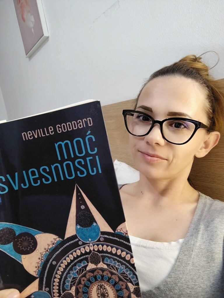 Woman reading The Power of Awareness by Neville Goddard in bed before sleep, living from the end evening routine